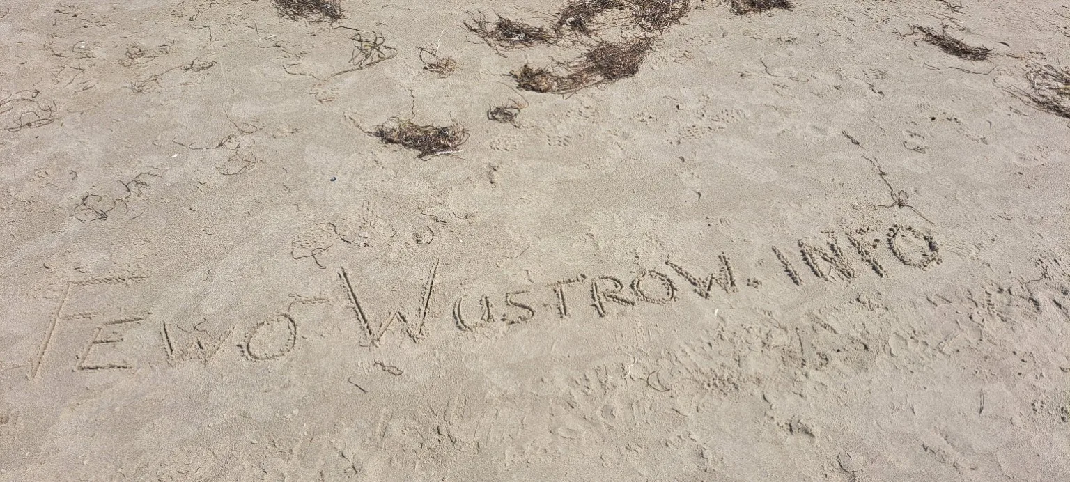 Der Schriftzug FEWO WUSTROW.INFO im Sand