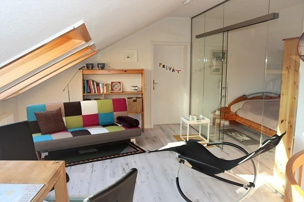 Dachgeschoss mit Sitz- und Schlafbereich hinter einer Glaswand